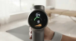 Digital LED display on a smart massage gun showing adjustable speed and pressure levels.